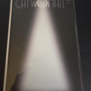 Puede incluir: Portada de cómic de "Catwoman" con efecto de foco. El título "CATWOMAN" está en la parte superior, con un símbolo de diamante. El número de la edición "39" está en la esquina superior derecha. Los nombres "HOWARD - LEON - BELLAIRE" están en la parte inferior.