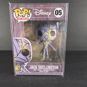 May include: A Jack Skellington vinyl figure from the Disney Pop! Art Series, displayed in its original packaging. The figure is predominantly purple with yellow accents, featuring a spiderweb design. The box has the Disney and Pop! logos.