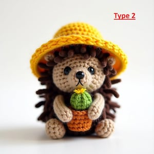 May include: A crocheted hedgehog wearing a yellow hat, holding a small green cactus in an orange pot. The hedgehog has brown spines and a tan face and arms. The text "Type 2" is in red.