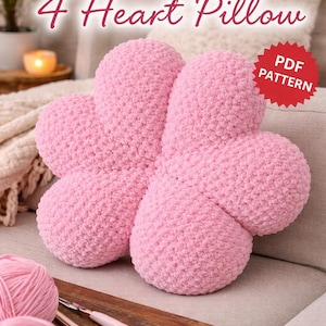 May include: A pink, four-heart-shaped crochet pillow. The pillow is made of a soft, textured yarn and sits on a light-coloured couch. The words "CROCHET PATTERN" and "4 Heart Pillow" are displayed at the top of the image. A red sticker says "PDF PATTERN".