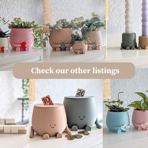 Puede incluir: Una colecci&oacute;n de macetas de cer&aacute;mica pintadas a mano, coloridas, con caras y patas lindas. Las macetas se muestran sobre una superficie blanca con plantas en su interior. El texto "Check our other listings" se muestra en el centro de la imagen.