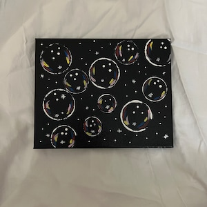 May include: A black canvas painting with white outlines of bubbles. The bubbles have colourful accents and white dots inside. The background is black with white stars.