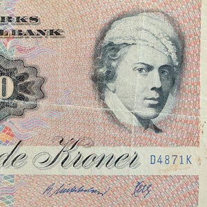May include: A Danish 100 Kroner banknote. The bill features a portrait of a man on the right side and the text "DANMARKS NATIONALBANK" at the top. The number "100" is prominently displayed in the centre, with the words "Hundrede Kroner" below.