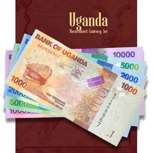 May include: A collection of Bank of Uganda banknotes in denominations of 1000, 2000, 5000, and 10000 shillings. The bills are layered over a dark red folder labelled Uganda Uncirculated Currency Set, featuring various colours including orange, blue, green, and purple.