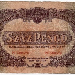Peut inclure: Un billet de banque hongrois vintage avec un design rouge et brun. Le billet présente une étoile rouge et le texte "SZÁZ PENGO" en grandes lettres grasses. Le billet comprend également le texte "A VOROSHADSEREG PARANCSNOKSACA" et "ELFOGADÁSA MINDEN FIZETÉSNÉL KÖTELEZŐ". Le billet est daté de 1944.