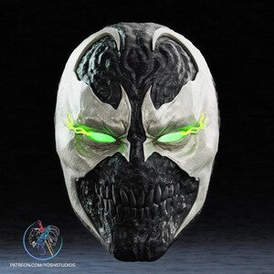 May include: A detailed mask with a menacing design, featuring a white face with black accents and glowing green eyes. The mask has a jagged, toothy mouth and a textured appearance. The text "PATREON.COM/YOSHSTUDIOS" is visible at the bottom.