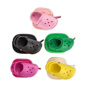 Pode incluir: Cinco chaveiros em miniatura com formato de sapato em diferentes cores: rosa, preto, verde, amarelo e rosa. Cada chaveiro tem uma pequena alça e um furo para prender as chaves.
