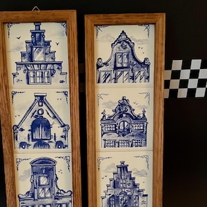 May include: Two wooden framed sets of blue and white Delft tiles depicting traditional Dutch houses. Each set features four tiles with different house designs.