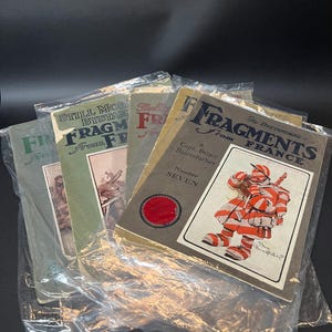 K&ouml;nnte beinhalten: Eine Sammlung von Vintage-Magazinen mit dem Titel "Fragments From France" in Plastikh&uuml;llen. Die Cover zeigen Illustrationen und Text, darunter "Still More Fragments" und "The Bystanders". Die Zeitschriften sind in verschiedenen Gr&uuml;n-, Grau- und Braunt&ouml;nen gehalten.