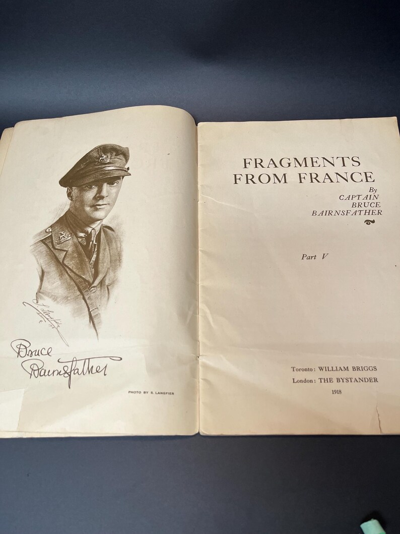 K&ouml;nnte beinhalten: Ein offenes Buch mit einem Portr&auml;t eines Mannes in Milit&auml;runiform und dem Titel "FRAGMENTS FROM FRANCE" von Captain Bruce Bairnsfather. Ver&ouml;ffentlicht 1918 von William Briggs in Toronto und The Bystander in London. Mit Unterschrift.
