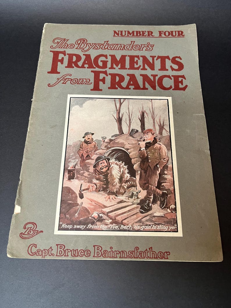 K&ouml;nnte beinhalten: Ein Vintage-Buchcover mit dem Titel "The Bystander's Fragments from France" mit einer Sepia-Illustration von Soldaten. Das Cover ist grau mit rotem Text, einschlie&szlig;lich des Namens des Autors, Capt. Bruce Bairnsfather, und einem Zitat.