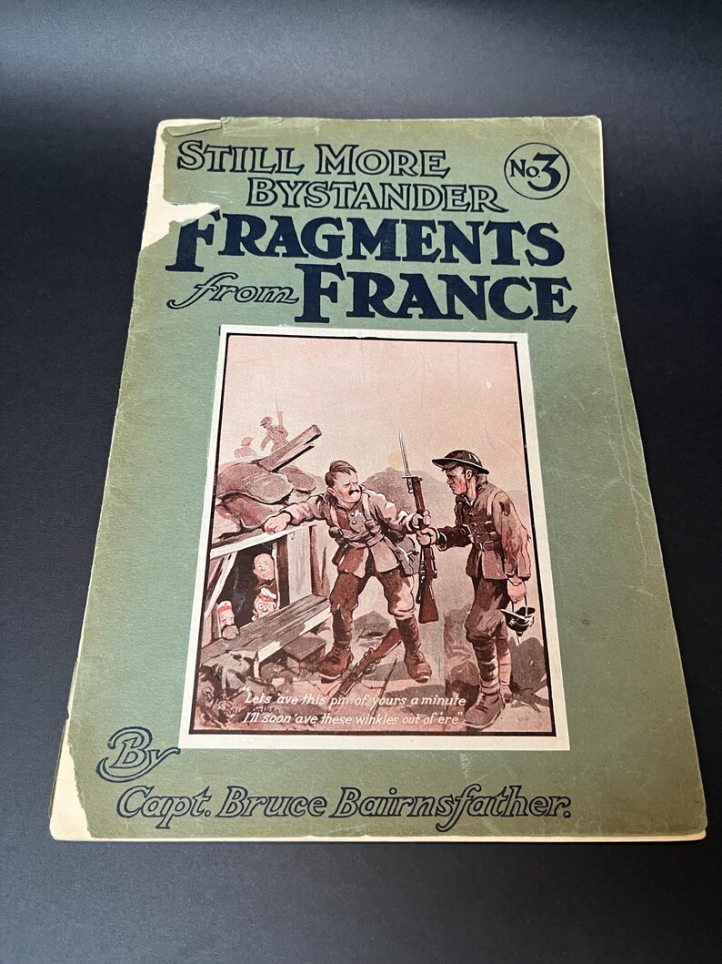 K&ouml;nnte beinhalten: Ein altes Buch mit dem Titel "Still More Bystander Fragments from France No. 3" von Capt. Bruce Bairnsfather. Das gr&uuml;ne Cover zeigt schwarzen Text und eine Illustration von Soldaten. Das Buch ist abgenutzt.