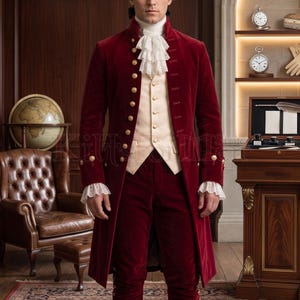 Close-up front view of a men's burgundy velvet 18th century coat with a tall standing collar, gold-tone button rows, cream waistcoat, and cascading white lace jabot. Styled with matching lace cuffs, this handmade Georgian gentleman's coat showcases rich colonial-era tailoring, ideal for historical reenactment, Bridgerton-style events, weddings, and period costume collectors seeking authentic 18th century menswear.