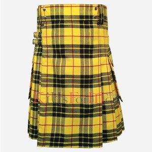 Op de afbeelding: Een gele, zwarte en rode tartan kilt met een utility-zak aan elke kant. De kilt heeft een gespsluiting en is gemaakt van een geweven stof.