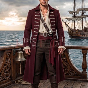 May include: A long, deep burgundy coat featuring silver-toned buttons and braided detailing, worn over a beige shirt and dark brown trousers. A brown leather belt with a silver buckle and a cross pendant necklace complete the ensemble.