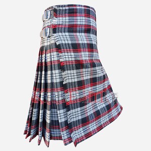 Puede incluir: Un kilt tradicional con un patrón de cuadros negros, rojos y blancos. El kilt tiene un borde con flecos y se asegura con dos hebillas plateadas.