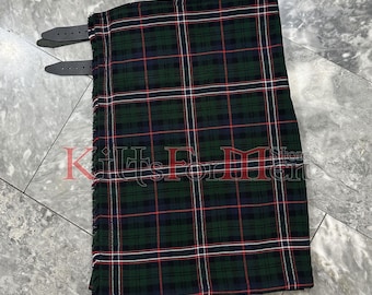 Op de afbeelding: Een groene, rode en witte tartan kilt met zwarte leren banden. De kilt is gemaakt van geweven stof en heeft een gefranst randje.