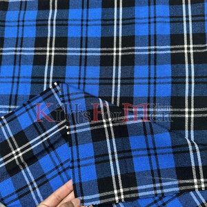 Pode incluir: Tecido xadrez azul, preto e branco com uma etiqueta branca e preta que diz "Kilts For Men" no centro.