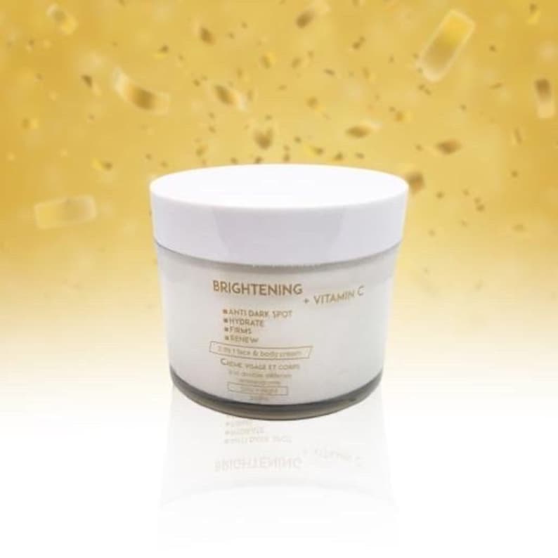 May include: White jar of brightening face and body cream with gold lettering that reads "BRIGHTENING + VITAMIN C" and lists the benefits: "ANTI DARK SPOT, HYDRATE, FIRMS, RENEW".