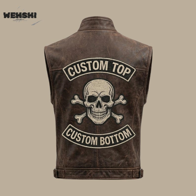 Puede incluir: Chaleco de cuero marr&oacute;n con un parche de calavera y huesos cruzados. El parche est&aacute; centrado en la espalda y tiene las palabras "CUSTOM TOP" y "CUSTOM BOTTOM" encima y debajo del gr&aacute;fico de la calavera. El chaleco tiene un estilo motero cl&aacute;sico.