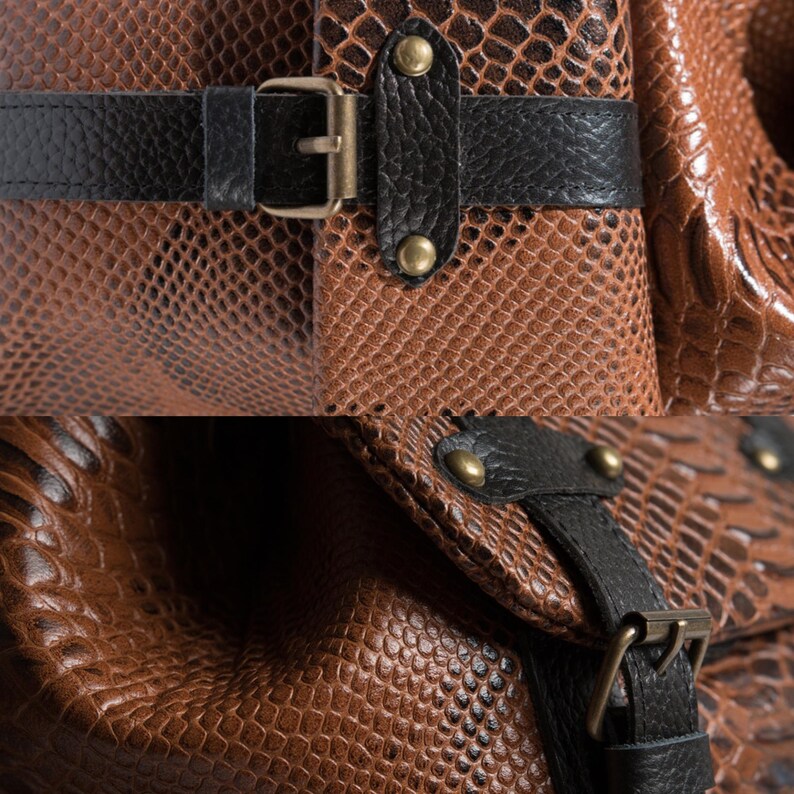 K&ouml;nnte beinhalten: Nahaufnahme einer braunen Ledertasche mit Schlangenmuster. Die Tasche hat schwarze Lederriemen und goldfarbene Metallbeschl&auml;ge, einschlie&szlig;lich Schnallen und Nieten. Die Textur des Leders ist sichtbar.