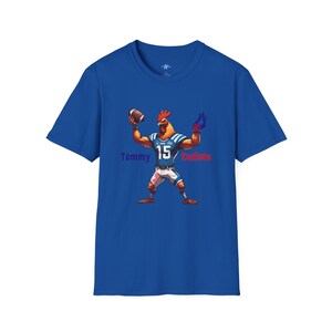 May include: A royal blue t-shirt with a cartoon rooster wearing a blue and white football jersey with the number 15. The rooster is holding a football and has a red and blue glove on one hand. The text "Tommy" is in purple and "Cotleets" is in red.