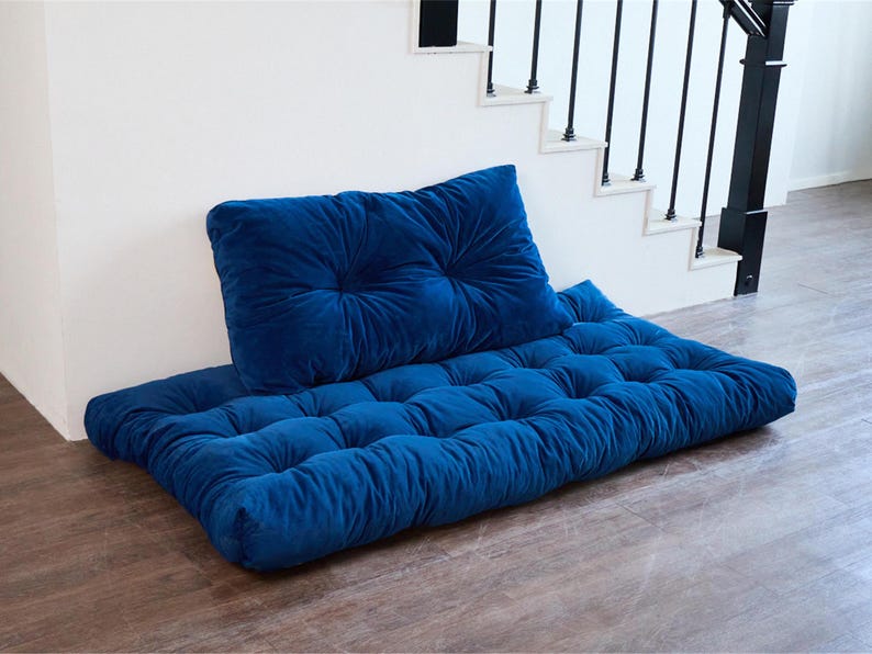 May include: A blue velvet floor cushion with a matching blue velvet pillow. The cushion is tufted and has a rectangular shape.