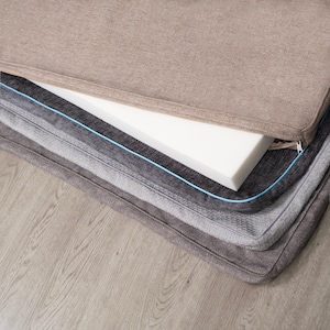 May include: A multi-layered dog bed with a beige outer layer, a white foam insert, and a grey inner layer. The bed is made of soft, comfortable fabric and has a zipper closure.