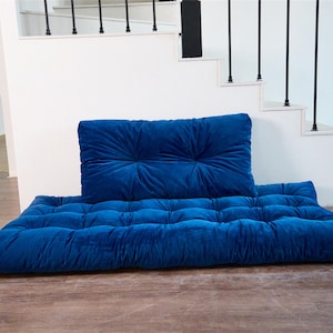 May include: A blue velvet floor cushion with a matching back cushion. The cushions are tufted and have a soft, plush texture.