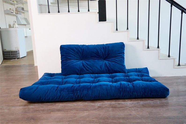 May include: A blue velvet floor cushion with a matching back cushion. The cushions are tufted and have a soft, plush texture.