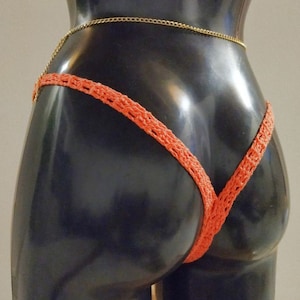 Peut inclure: Un bas de bikini en crochet de couleur corail avec une fine ceinture en chaîne dorée.