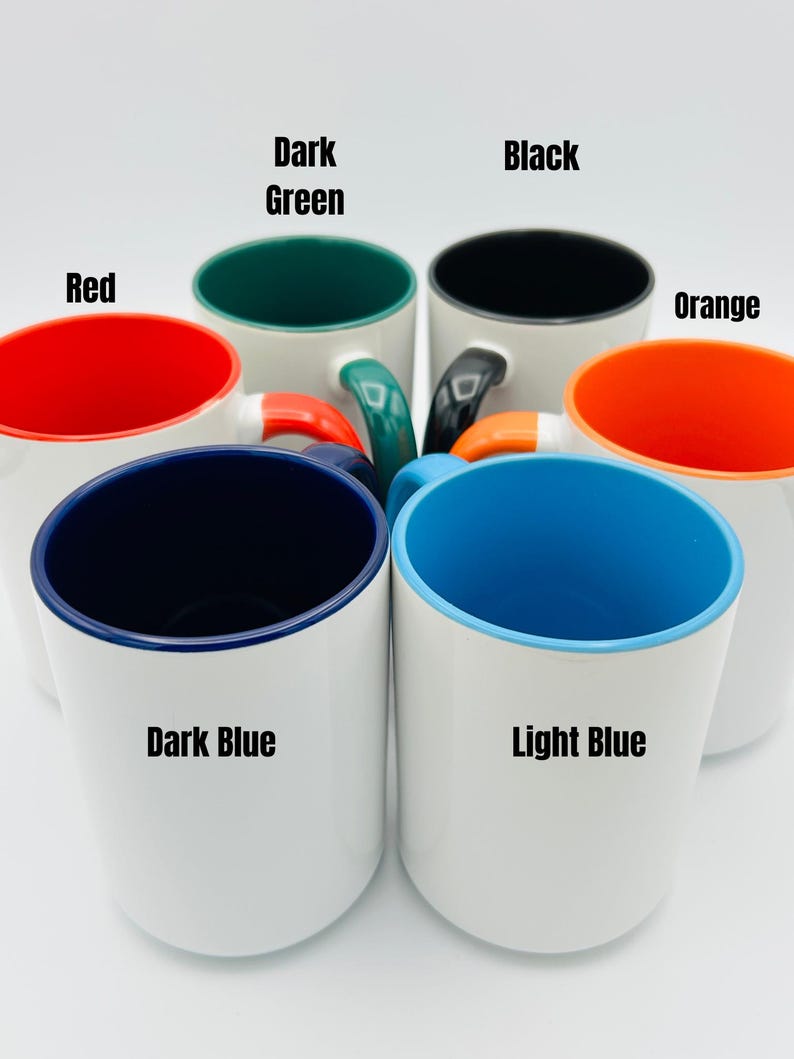 May include: A collection of white ceramic mugs with colored interiors and handles. The interior colors include red, dark green, black, orange, dark blue, and light blue. Each mug has the interior color labeled on the side.