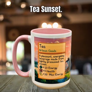 May include: A white ceramic mug with a pink handle and rim, featuring a label that reads "Tea Artisan Goods." The label describes the tea as an energizing beverage. The mug has the text "Tea Sunset" at the top.