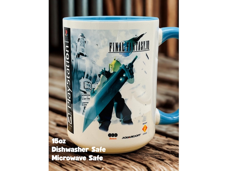 Op de afbeelding: Een witte keramische Final Fantasy VII-mok met een blauw handvat en rand. De mok heeft een karakterillustratie met een groot zwaard en het logo van de game. De tekst "PlayStation" is zichtbaar aan de zijkant. De mok is ongeveer 444 ml en is vaatwasser- en magnetronbestendig.