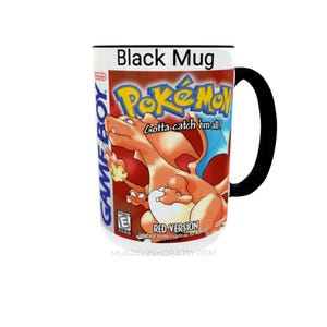 May include: A black ceramic mug featuring the Nintendo Game Boy Pok&eacute;mon Red Version video game cover art. The design includes the orange Charizard character, the Pok&eacute;mon logo, the text Gotta catch 'em all!, and the ESRB E rating symbol.
