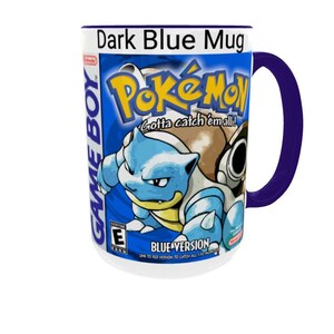 May include: A dark blue ceramic mug featuring a graphic print of the Pok&eacute;mon Blue Version Game Boy video game cover art. The design includes the Pok&eacute;mon Blastoise, the Pok&eacute;mon logo, the text Game Boy, and the ESRB rating E for everyone.