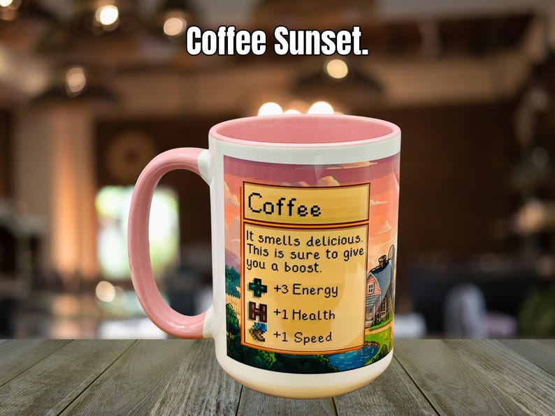 May include: A white coffee mug with a pink handle and rim, featuring a sunset design and the text "Coffee Sunset." The mug has a graphic with the word "Coffee" and text that reads "It smells delicious. This is sure to give you a boost."