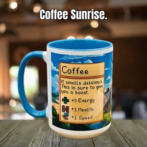 May include: A white ceramic mug with a blue handle and rim, featuring the text "Coffee Sunrise." The mug has a colorful design with the word "Coffee" and text that reads "It smells delicious. This is sure to give you a boost." The design also includes +3 Energy, +1 Health, and +1 Speed.