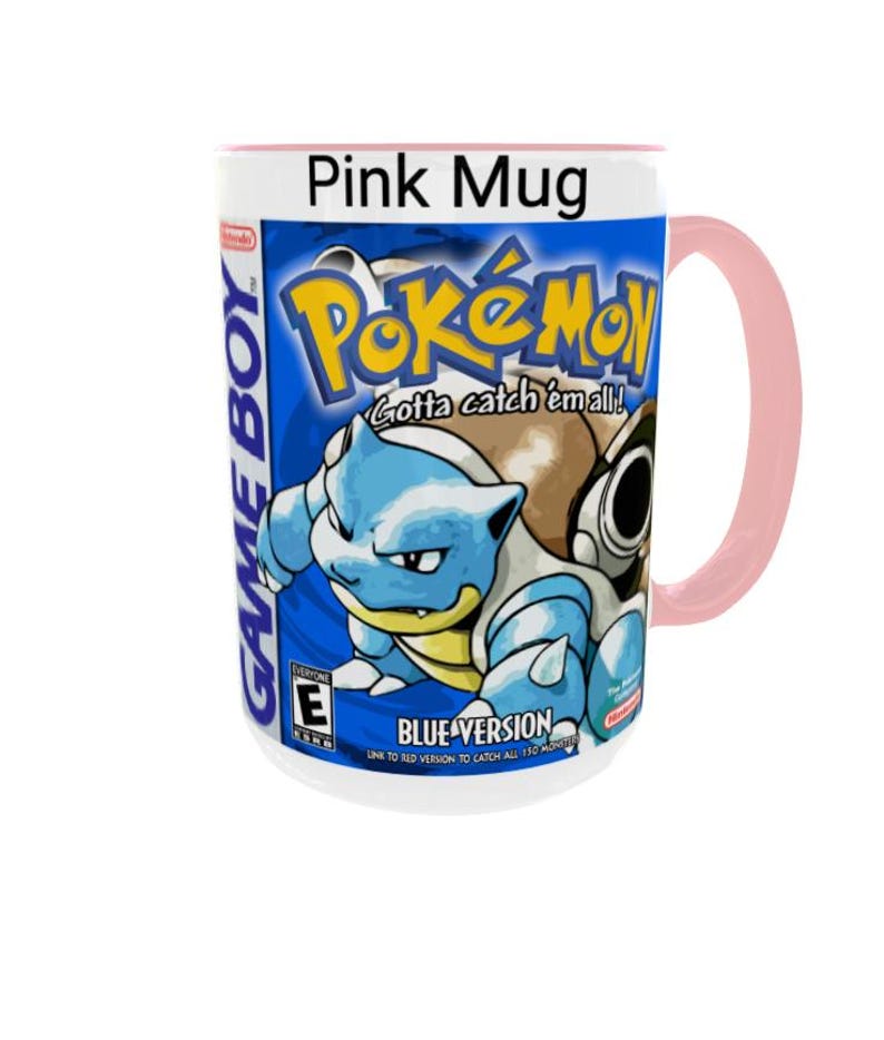May include: A pink ceramic mug featuring a graphic print of the Game Boy Pok&eacute;mon Blue Version video game cover art. The design includes the Pok&eacute;mon Blastoise, the Pok&eacute;mon logo, the text Gotta catch 'em all!, Blue Version, and an ESRB E rating.