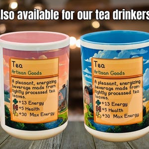 May include: Two ceramic mugs with colorful designs. One mug has a pink handle and interior, the other has a blue handle and interior. Both mugs feature a label with the word "Tea" and a description of the beverage.