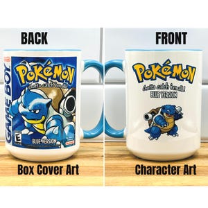 May include: A white ceramic mug with a blue handle and interior rim. One side features the Pok&eacute;mon Blue Version Game Boy box art with Blastoise. The other side displays the Pok&eacute;mon logo, the text Blue Version, and a pixelated Blastoise character.