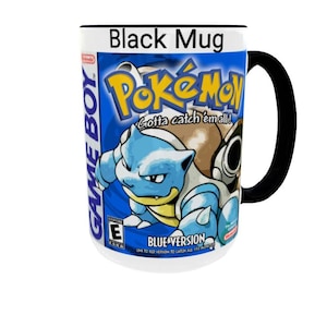 May include: A black ceramic mug featuring a graphic print of the Pok&eacute;mon Blue Version Game Boy game cover. The design includes the Pok&eacute;mon logo, the text Gotta catch 'em all!, Blastoise, the Game Boy logo, and the ESRB E rating symbol.