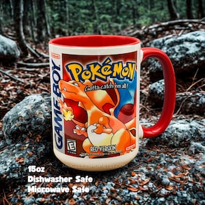 May include: A 15oz ceramic mug with a red interior and handle, featuring a graphic of the Pokemon Red Version Game Boy game box art, including the Charizard illustration, the Pokemon logo, and the text Gotta catch em all and Nintendo.