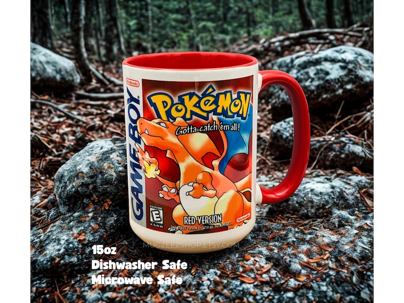May include: A 15oz ceramic mug with a red interior and handle, featuring a graphic of the Pokemon Red Version Game Boy game box art, including the Charizard illustration, the Pokemon logo, and the text Gotta catch em all and Nintendo.