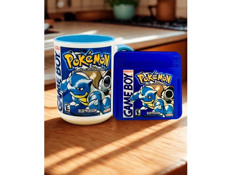 May include: A white ceramic mug with a blue interior and a matching blue Game Boy Pok&eacute;mon Blue Version game cartridge. The mug and cartridge both feature the Pok&eacute;mon logo, the text Game Boy, and an illustration of the character Blastoise.