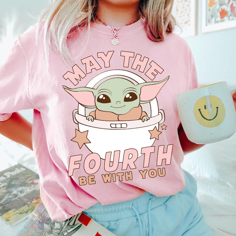 a woman wearing a pink shirt with a baby yoda on it