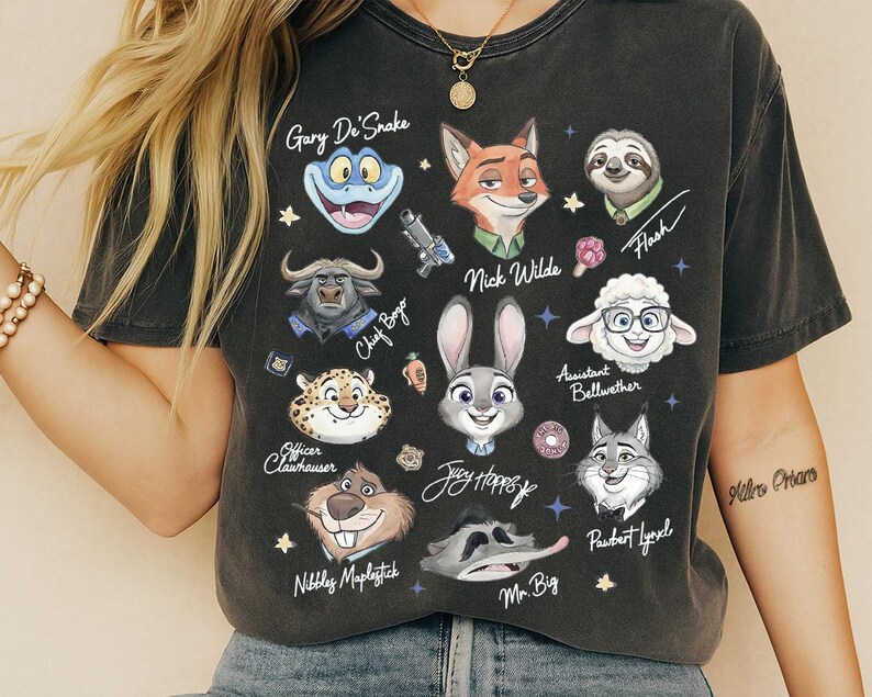 A person wearing a black t-shirt with various cartoon animal characters printed on it, including a frog, a snake, a cow, a pig, a lion, a dog, a rabbit, a cat, and a bear.
