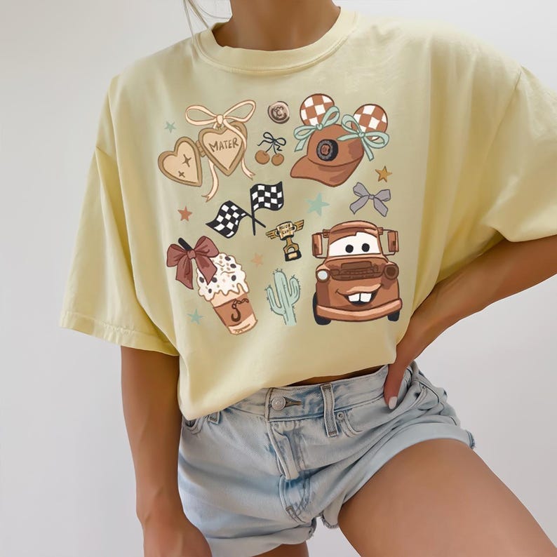 a woman wearing a yellow shirt with cars on it