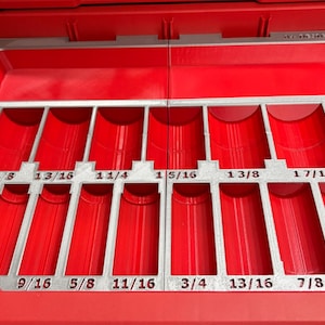 May include: Red tool organizer with multiple compartments and labeled slots for various sized tools. The slots are labeled with fractional inch measurements, such as 1/2, 5/8, and 3/4. The organizer is designed to keep tools organized.