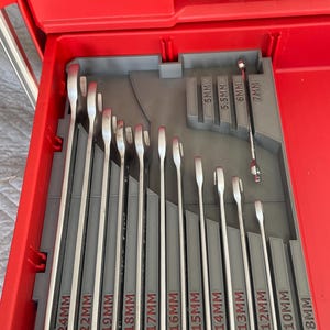 May include: A set of wrenches organised in a grey plastic tray with labelled slots for each size. The wrenches are silver and range in size from 8mm to 24mm. The tray is in a red toolbox.